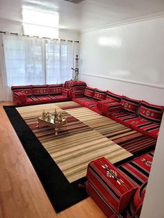 a living room filled with lots of red couches and rugs on top of a hard wood floor