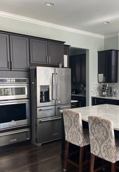 a kitchen with black cabinets and silver appliances