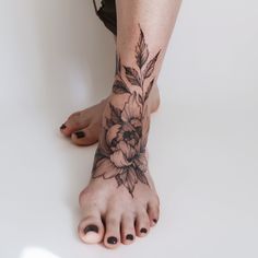 a woman's foot with flowers and leaves tattooed on her left leg, while the lower part of her body is visible