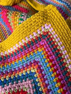 a colorful crocheted blanket is laying on the floor