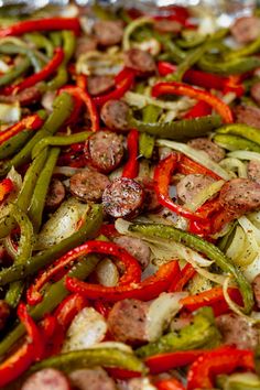 a pan filled with sausage, green beans and red bell peppers on top of aluminum foil