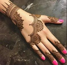 a woman's hand with henna tattoos on her left arm and pink nails