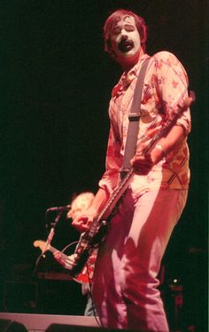 a man with his face painted like a clown holding a guitar in front of him