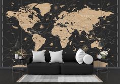 a living room with a black couch and large wall map on the wall behind it