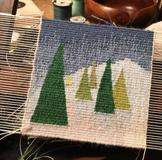 a close up of a piece of cloth with trees on it and other items in the background