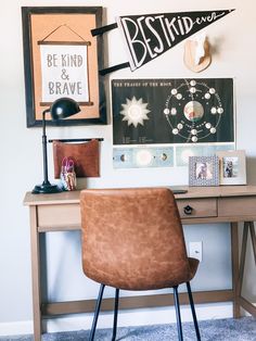 a brown chair sitting in front of a desk with pictures on the wall behind it