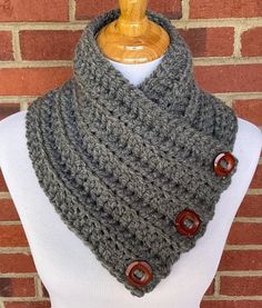 a gray knitted cowl with buttons is on a mannequin headpiece