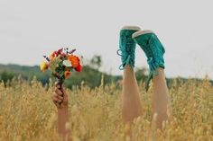 a person with their feet in the air holding flowers