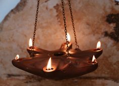 three lit candles hanging from chains on a wall