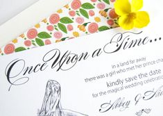 a wedding card with a yellow flower on the front and back side, sitting next to an envelope that says once upon a time