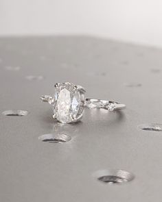 a diamond ring sitting on top of a silver surface with drops of water around it