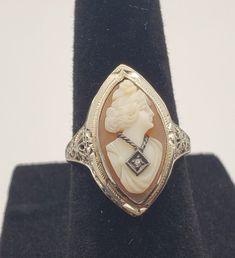 Absolutely gorgeous carved shell cameo ring. It has very delicate filigree white gold setting with a white sapphire accent (lady's pendant). The ring has it's unique style, which would make it noticeable by others. It will make a great addition to anyone's jewelry collection. The ring comes with a box, in which it was purchased in the Girard Jeweler's shop back in 1950'-1960'. Ring is in a awesome antique condition with minimal signs of wear (considering it's age). White Gold Set, Cameo Ring, Carved Shell, Deco Ring, Art Deco Ring, White Sapphire, Unique Style, Jewelry Collection, Jewelry Watches