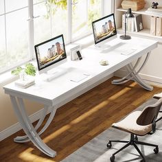 a computer desk with two monitors and a laptop on it in front of a window