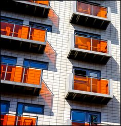 an apartment building with orange windows and balconies