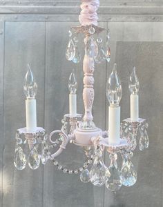 a white chandelier hanging from the ceiling with crystal beads and candles on it