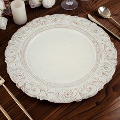 a white plate sitting on top of a wooden table next to silverware and candles