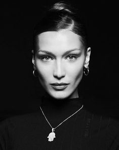 a black and white photo of a woman wearing a necklace with a hamsa on it