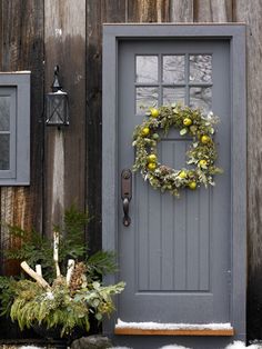 a gray front door with a wreath on it