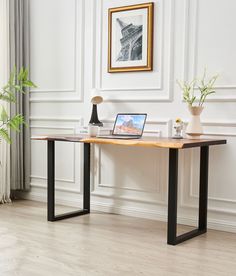 a laptop computer sitting on top of a wooden desk next to a potted plant