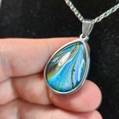 This inviting pendant features beautiful metallic ribbons of blue and gold, flowing in a graceful swoop. Every Flow Pendant is one-of-a-kind, hand-painted and preserved beneath a crystal-clear glass bezel. Each piece in the Flow series features a high quality stainless steel pendant, hung on an included 20" stainless steel chain with a lobster clasp. Stainless steel is affordable and durable; not only shiny but also non-tarnishing and scratch resistant. Because it is hypoallergenic, it is also an excellent choice for people with sensitive skin. Affordable Unique Glass Necklaces, Bezel Necklace, Painted Glass, Stainless Steel Pendant, Art Jewelry, Steel Chain, Custom Art, Stainless Steel Chain, Crystal Clear