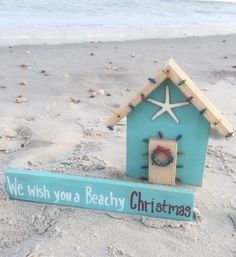 a small blue house with a starfish on it and a sign that says, we wish you a beachy christmas