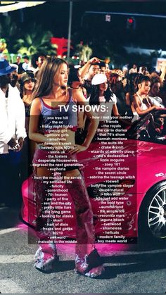 a woman standing next to a pink car in front of a large group of people