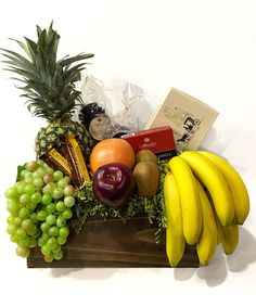 a fruit basket with bananas, pineapples, oranges, grapes and other fruits