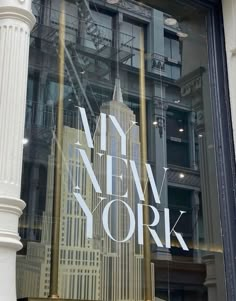 new york city's empire building is reflected in the window of a storefront