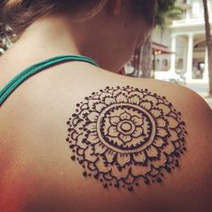 a woman's back with a tattoo on her shoulder and the image of a flower