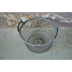 a metal basket sitting on top of a cement floor