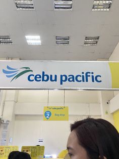 people are standing in front of a sign that says cebu pacific on the ceiling