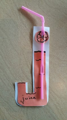 the letter j is made out of paper and has a pink straw in it with writing on