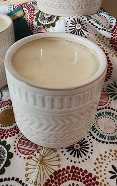 two white bowls filled with liquid sitting on top of a table covered in floral designs