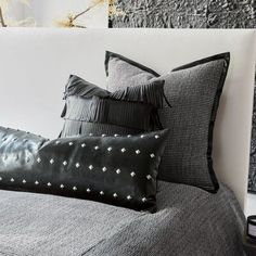 a black and white bed with two pillows on it's headboard next to a plant