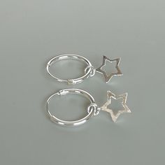 A PAIR of sterling silver hoops. Comes with a detachable tiny and delicate star charm. The charm is multipurpose and can be used with a neck or bracelet chain too. Dimension: Hoop- 12 x 1.2 mm Charm- 6 x 6 mm Weight: 0.97 gm Price listed is for a PAIR of hoops. These earrings are made of 925 hypoallergenic sterling silver and comes with a 925 stamp. Can be packaged in a gift box. I can include a personal message from you if needed You are welcome to contact me at... bhavnakwintra1956@gmail.com F Silver Dangle Hoop Earrings With Star Charm, Minimalist Silver Star Hoop Earrings, Sterling Silver Star Charm Huggie Earrings, Silver Star-shaped Minimalist Huggie Earrings, Sterling Silver Star Charm Cartilage Earrings, Silver Star Huggie Earrings For Everyday, Minimalist Star-shaped Sterling Silver Huggie Earrings, Silver Star-shaped Hoop Earrings For Everyday, Silver Star Huggie Earrings Minimalist Style