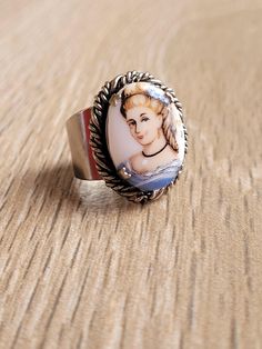 "This is a beautiful vintage cameo porcelain ring. With a lady in blue (victorian familiar image) over the white porcelain inlay in a silver tone ring with a great swirled silver rim work. Condition: As found. Good vintage condition (please see photos carefully) These are vintage items and, as they have been previously loved, they may show signs of wear and age. Measures: front of the ring 2,2cm x 1,6cm / 7/8\" x 5/8\" Weight 6,5gr Shipping with tracking." Vintage Enamel Cabochon Rings, Vintage Enamel Cameo Jewelry, Vintage Cameo Enamel Jewelry, Vintage Cameo Jewelry In Enamel, Vintage Oval Enamel Ring Gift, White Cameo Ring For Gift, Vintage White Oval Cabochon Ring, Vintage Silver Enamel Ring For Wedding, Vintage White Cabochon Jewelry