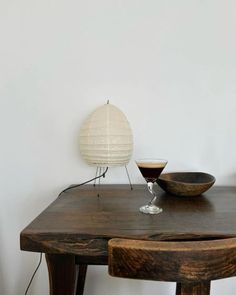 a wooden table topped with a bowl and lamp