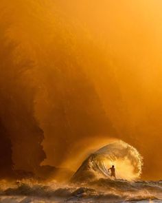 a person riding a wave on top of a surfboard in the ocean under an orange sky