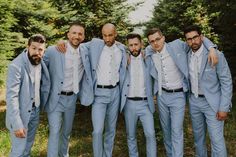 a group of men standing next to each other wearing blue suits and white shirts with their arms around one another