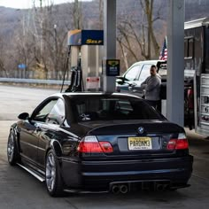 a black bmw parked at a gas station