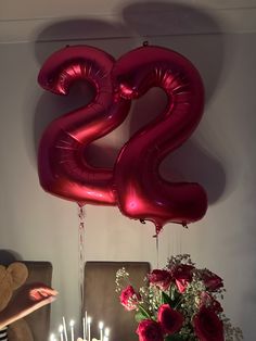 the number twenty two balloons are hanging above a table with flowers and candles on it