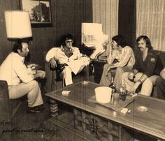 black and white photograph of four people sitting in a living room