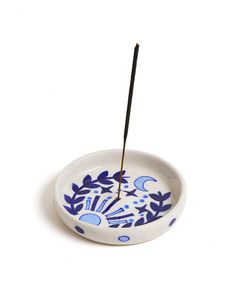 a blue and white bowl with a black stick sticking out of it's center