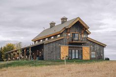 a large wooden building sitting on top of a lush green field next to tall grass