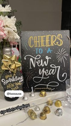 a sign that says cheers to a new year next to some chocolates and flowers