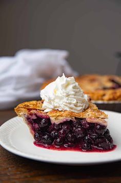 a piece of pie with whipped cream on top is sitting on a plate next to another pie