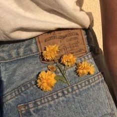 yellow flowers are sticking out of the back pocket of someone's jeans