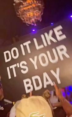 a man holding up a sign that says do it like it's your bday