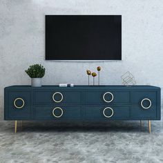 a blue dresser with gold handles in front of a flat screen tv mounted on the wall