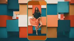 a woman standing in front of a colorful wall with an orange and blue cell phone